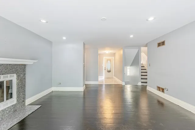 a view of an empty room with wooden floor and a fireplace
