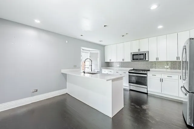 a kitchen with white cabinets appliances and sink