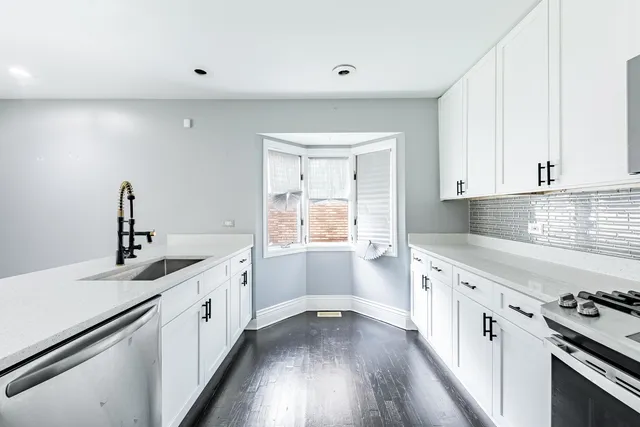 a kitchen with granite countertop a sink stove and cabinets