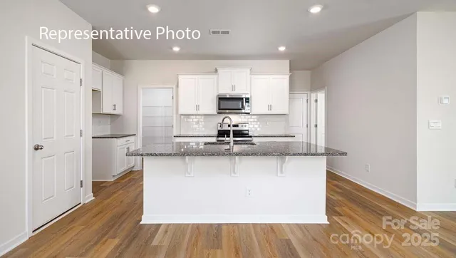 a large kitchen with stainless steel appliances granite countertop a stove a refrigerator and a microwave