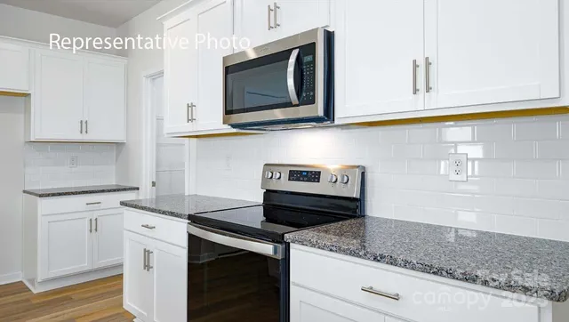 a kitchen with granite countertop cabinets stainless steel appliances and wooden floor
