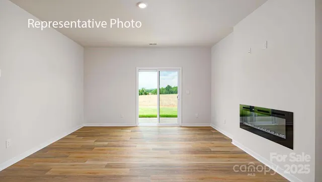 a view of empty room with wooden floor and fireplace