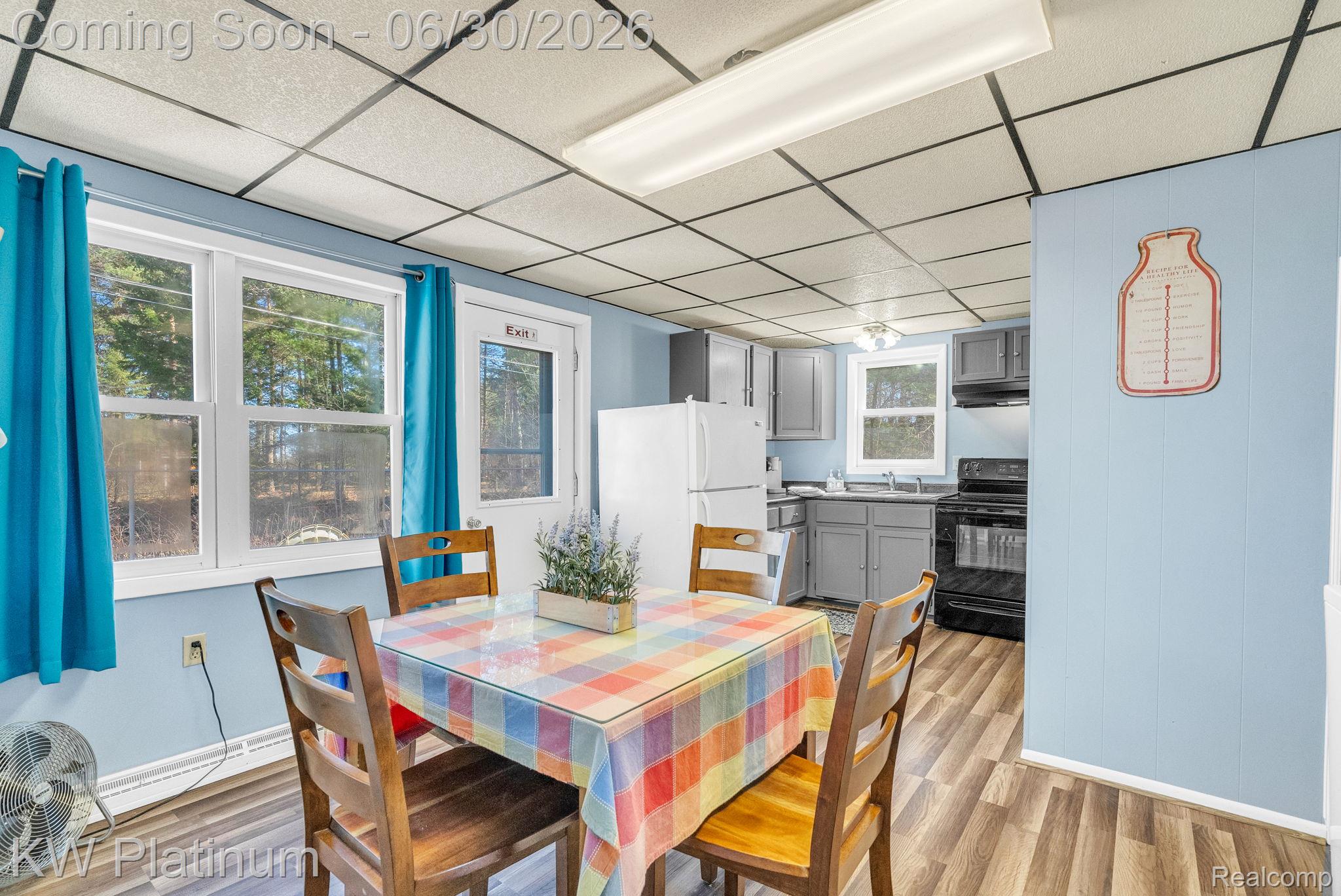 2235 South Lake Shore Road Harbor Beach, MI 48441 - Photo 70 of 99 Kitchen and dining area featuring wood-finish flooring, light blue paneling, white window frames, and a drop ceiling with fluorescent lighting