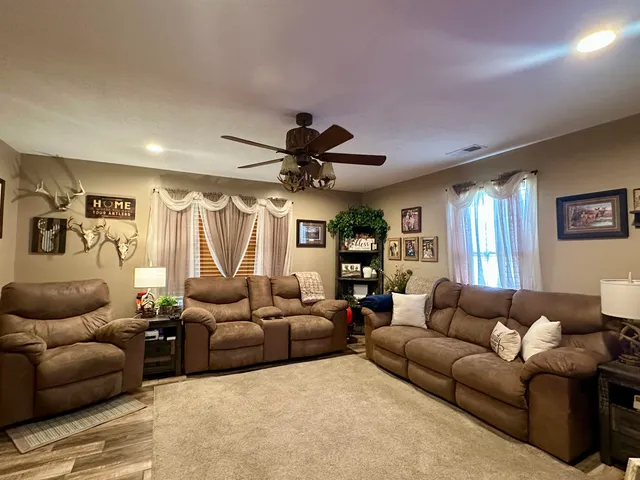 a living room with furniture a ceiling fan and a window