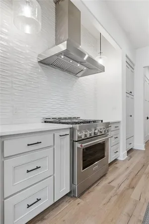 a kitchen with white cabinets stainless steel appliances and wooden floor