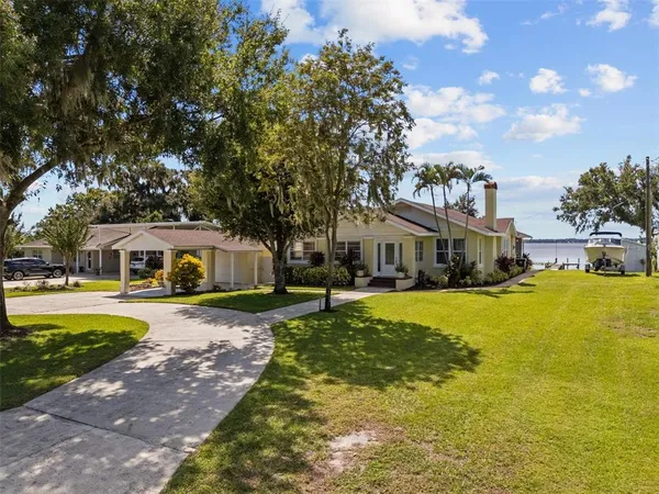 a front view of a house with a big yard and large trees