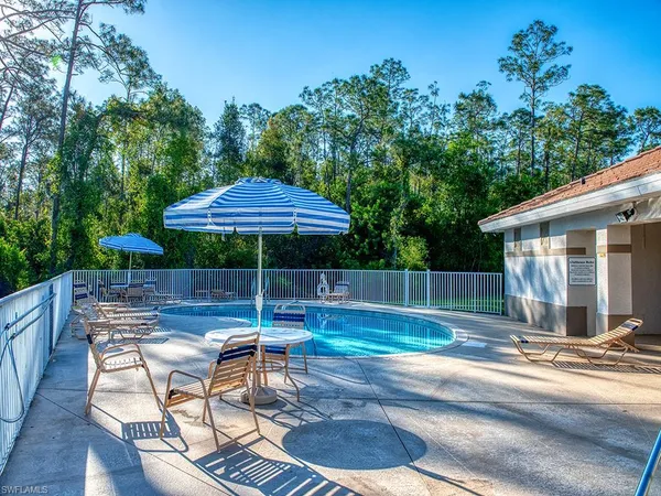 a view of a backyard with table and chairs under an umbrella with wooden fence