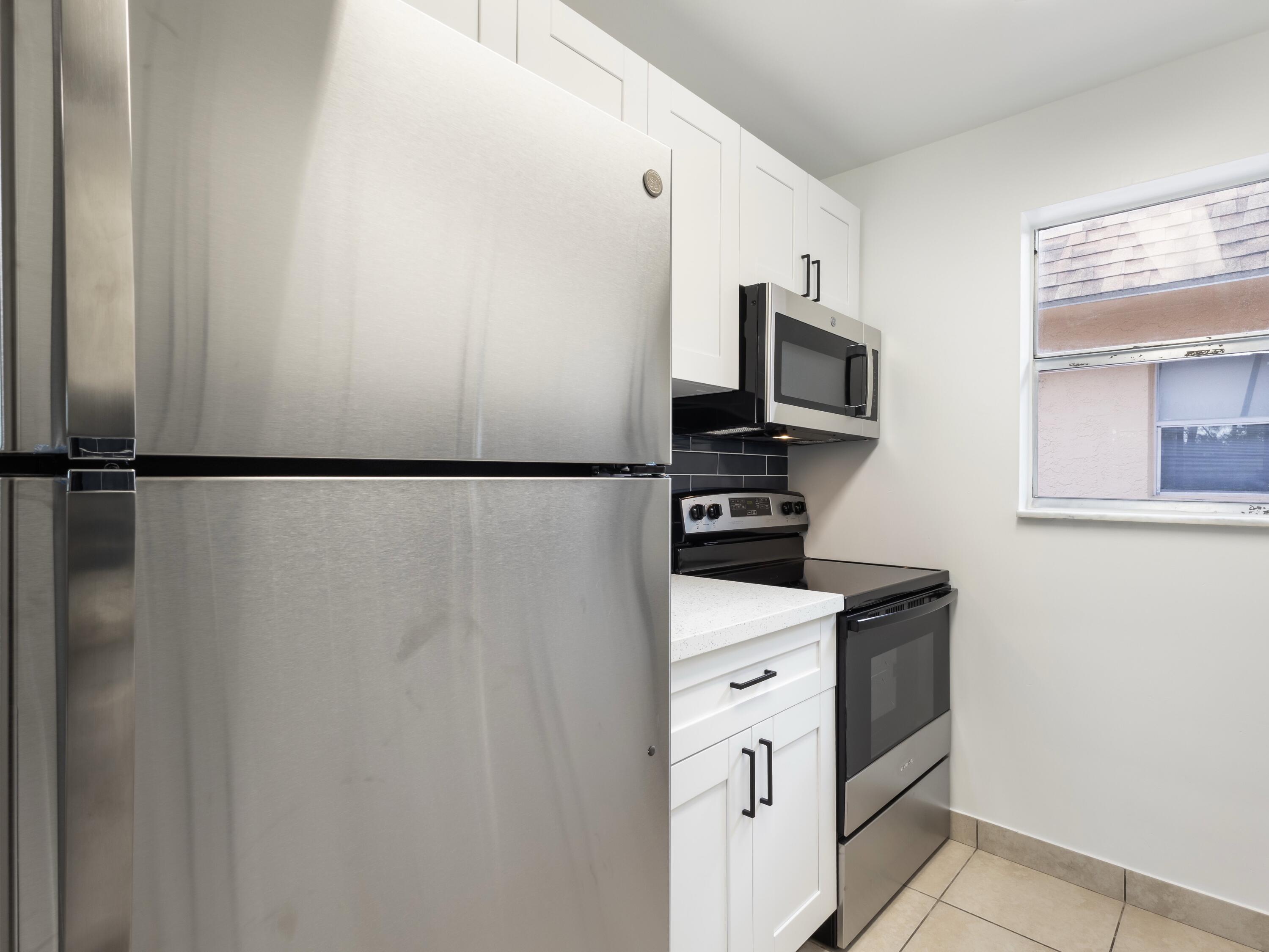 450 Southwest 2nd Avenue, Unit 2050 Boca Raton, FL 33432 - Photo 2 of 11 a kitchen with stainless steel appliances white cabinets and a refrigerator