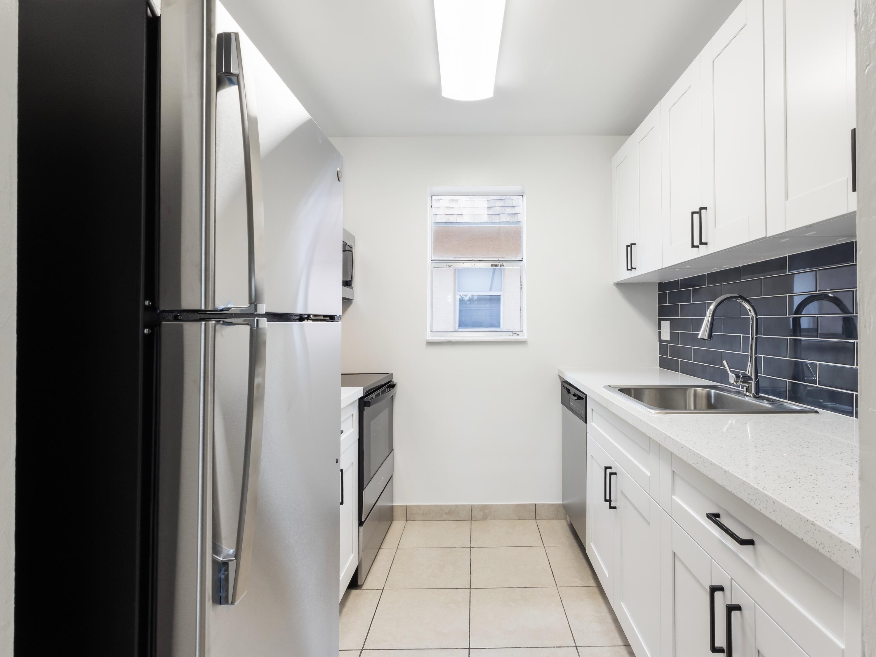 450 Southwest 2nd Avenue, Unit 2050 Boca Raton, FL 33432 - Photo 3 of 11 a kitchen with a sink a refrigerator and cabinets
