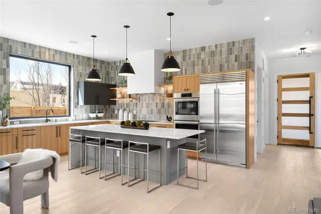 a kitchen with stainless steel appliances a stove a sink a refrigerator a center island and a wooden floor