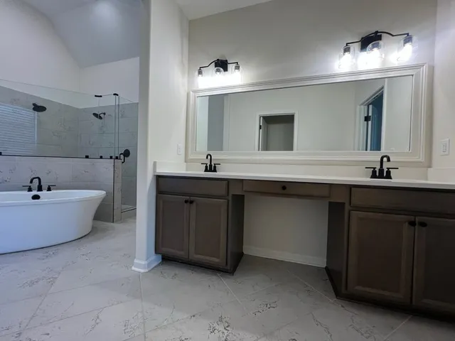 a bathroom with a tub a double vanity sink and mirror