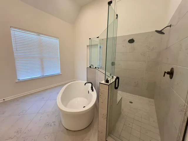 a bathroom with a tub a window and a shower
