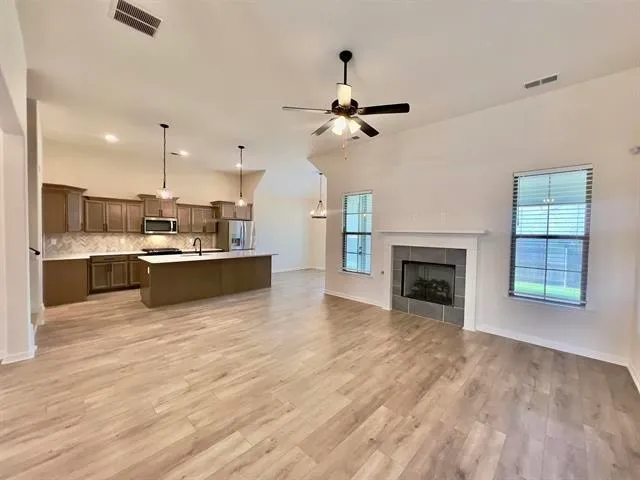 a view of a kitchen with kitchen island wooden floor and a fireplace