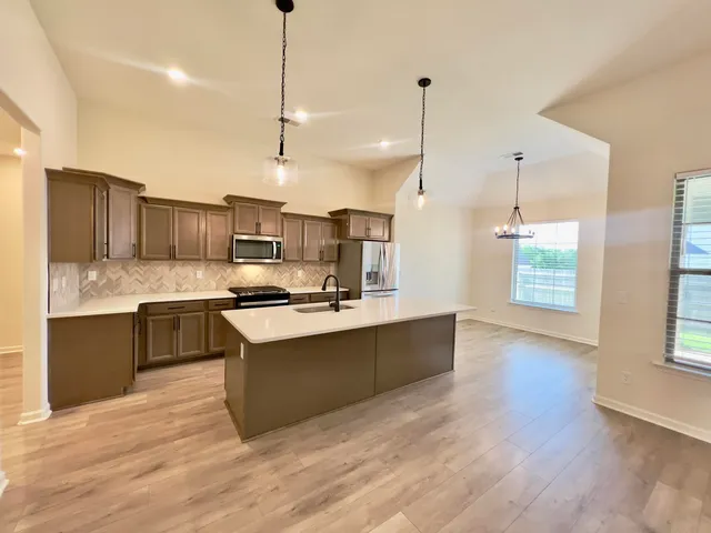 a kitchen with stainless steel appliances granite countertop a sink a stove and a wooden floors