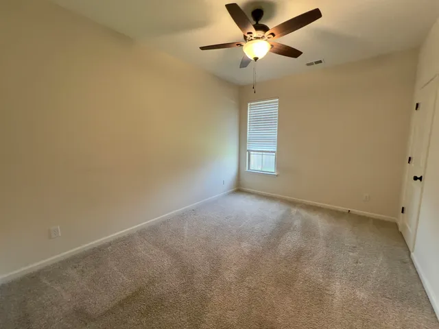 an empty room with a chandelier fan and windows