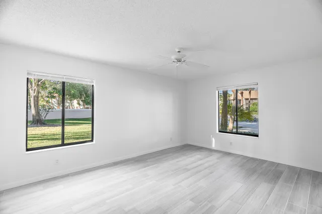 a view of an empty room with a window and wooden floor