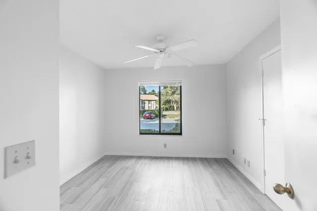 an empty room with a window and a ceiling fan