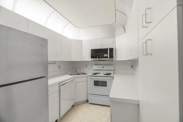 a kitchen with a sink white cabinets and white appliances
