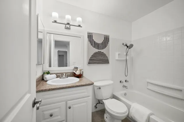 a bathroom with a granite countertop sink mirror toilet and bathtub