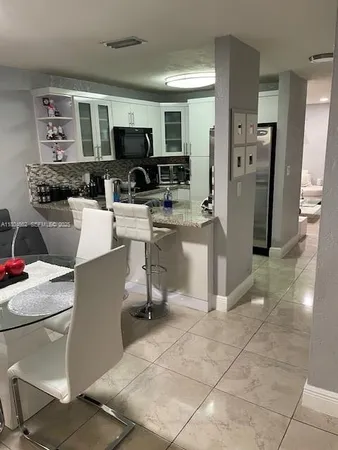 a living room with stainless steel appliances a couch cabinets and a window