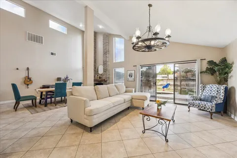 a living room with couch a dining table and a chandelier