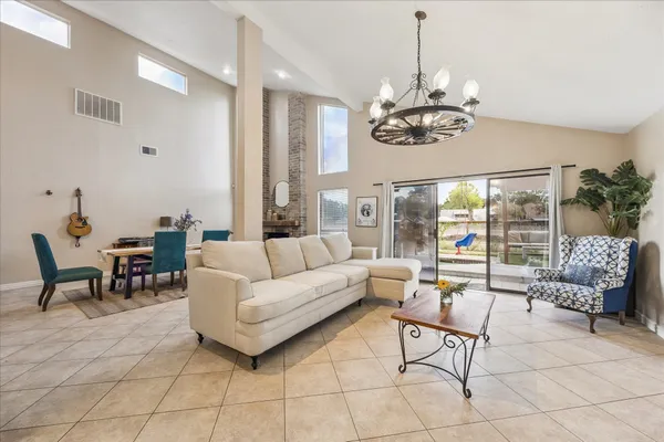 a living room with couch a dining table and a chandelier