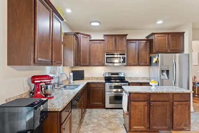 a kitchen with stainless steel appliances granite countertop a sink stove refrigerator and cabinets