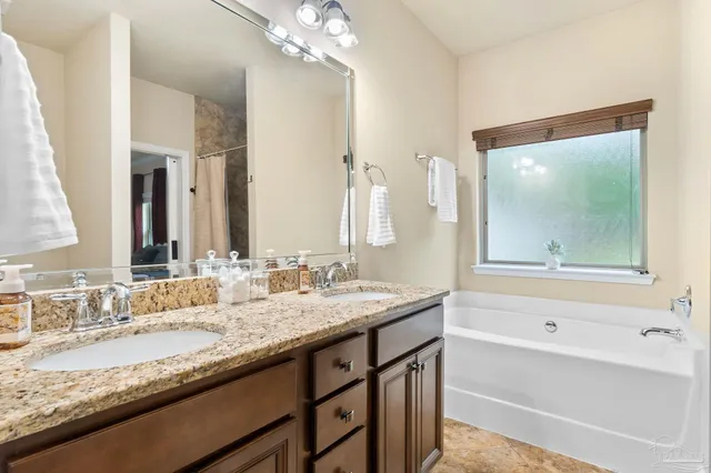 a bathroom with a granite countertop bathtub a sink and a mirror