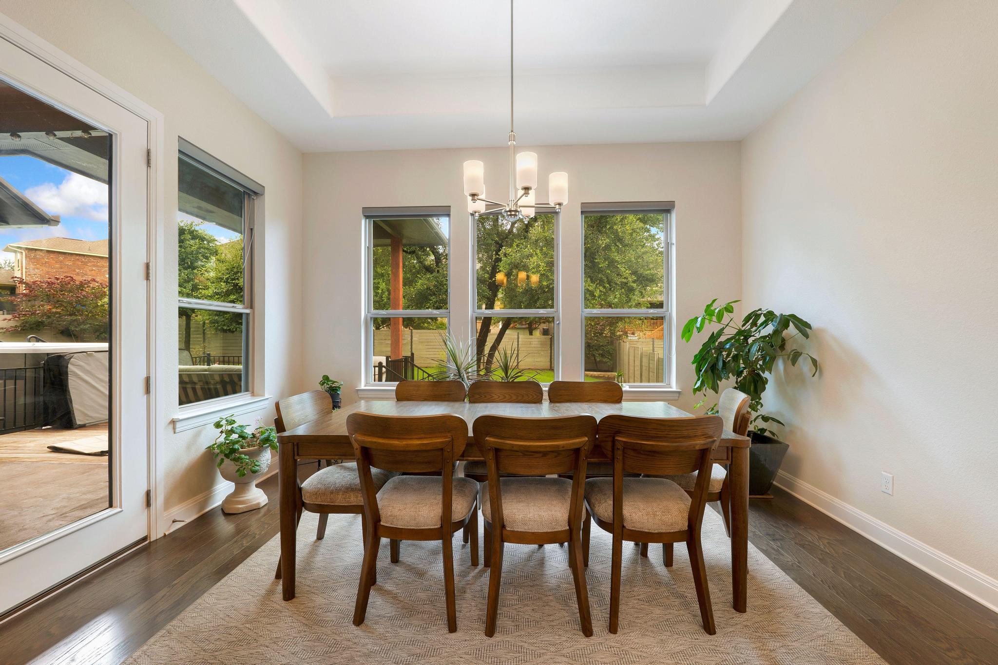 1009 Legacy Crossing Georgetown, TX 78628 - Photo 29 of 40 A refined dining space features a warm hardwood floor, multiple windows, and a classic chandelier, ideal for elegant meals.