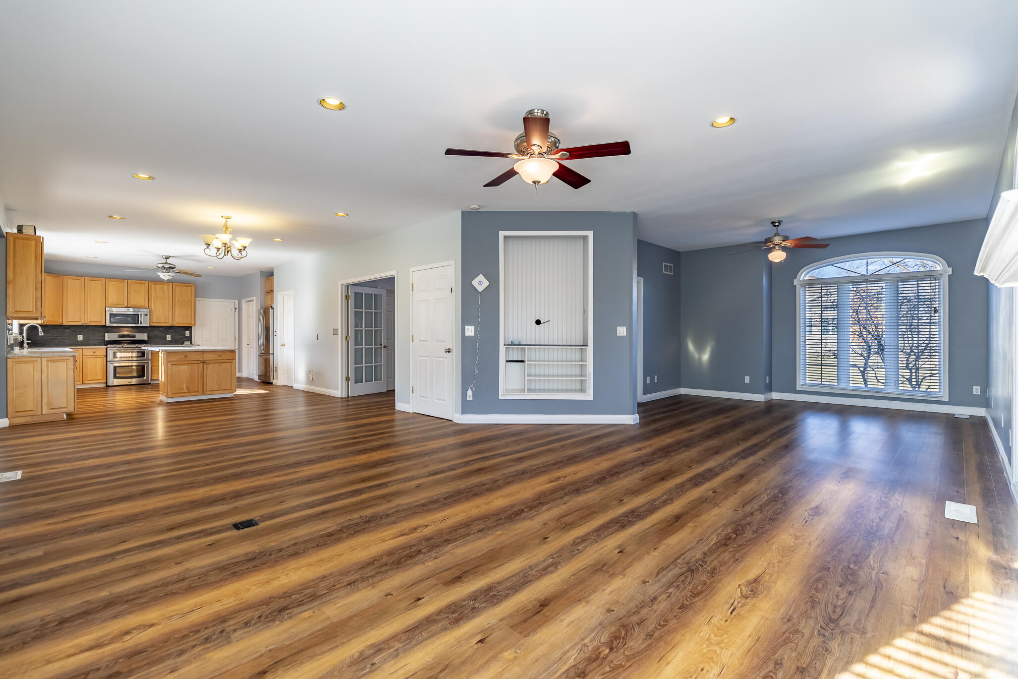 8049 West 85th Court Crown Point, IN 46307 - Photo 24 of 47 a view of an empty room with wooden floor and a kitchen