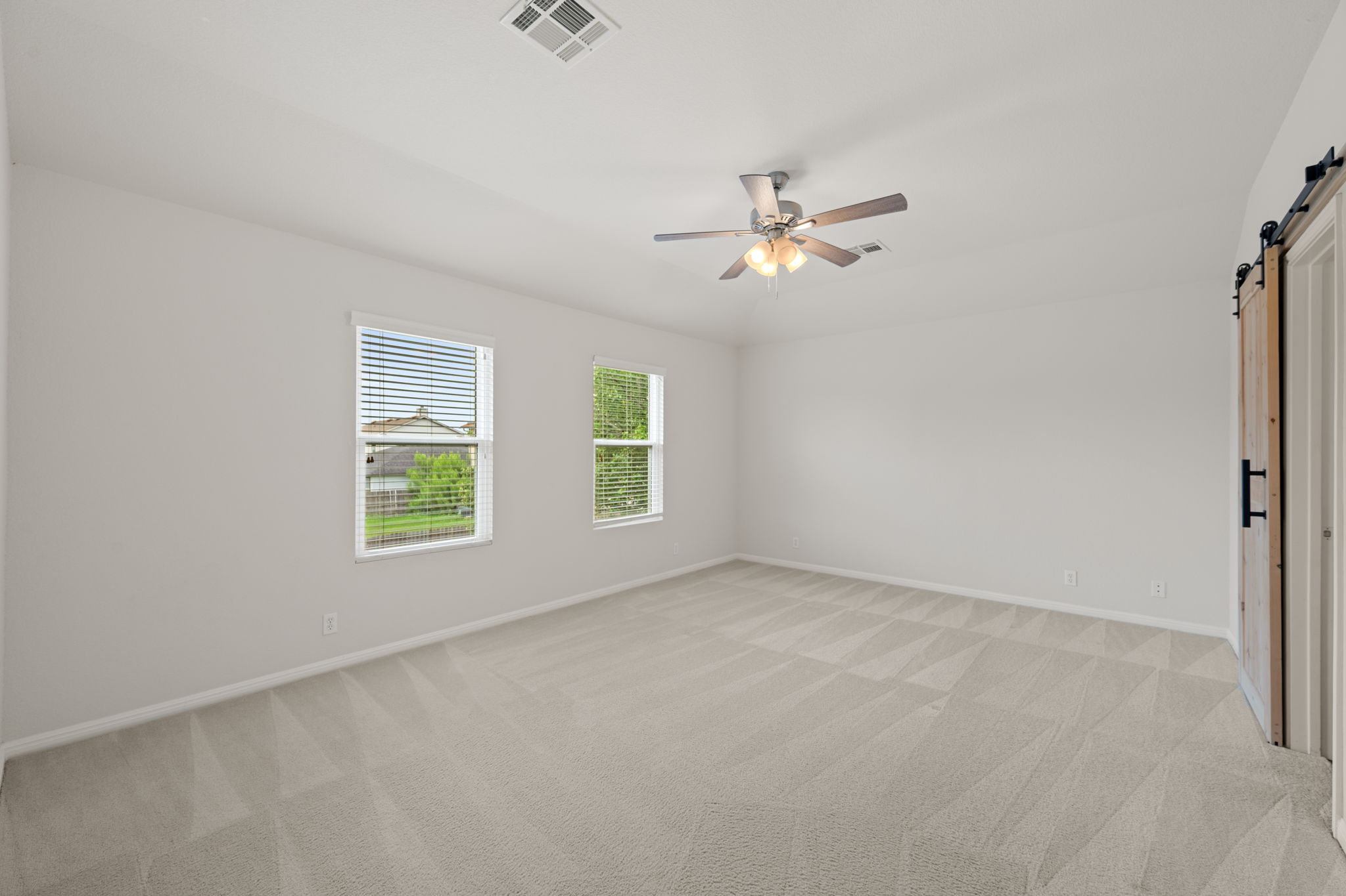 8902 Magna Carta Loop, Unit 122 Austin, TX 78754 - Photo 16 of 39 A spacious, naturally illuminated room features plush carpeting and a modern ceiling fan.