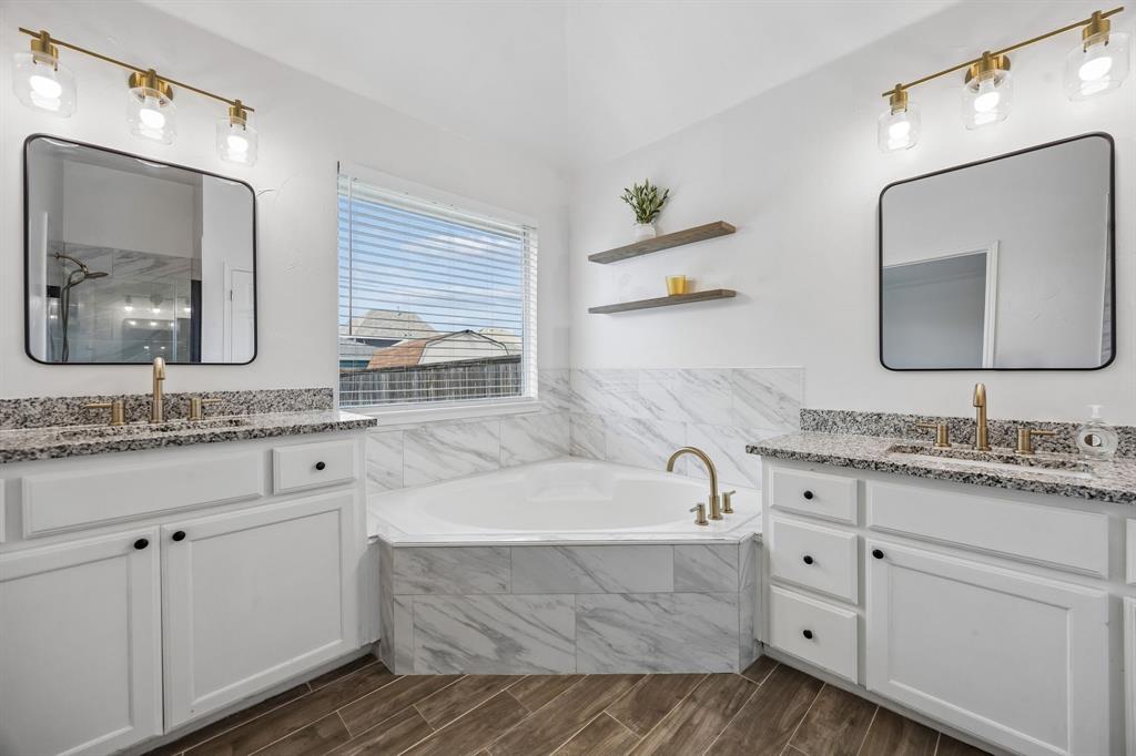 9217 Inverness Drive Rowlett, TX 75089 - Photo 21 of 40 Dual Vanity Bath with Soaking Tub — Separate vanities, updated tile surround, and a soaking tub create a well-designed bath with space to unwind and reset.