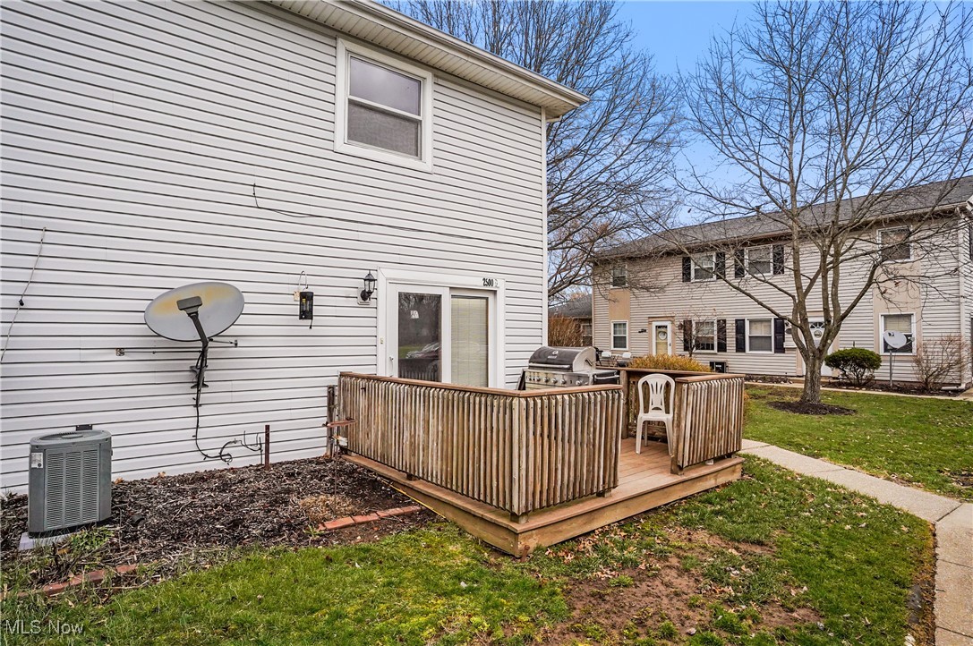 2500 Raber Road Uniontown, OH 44685 - Photo 7 of 31 Rear view of property with central AC unit, a lawn, and a wooden deck