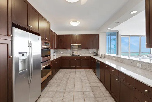 a large kitchen with stainless steel appliances granite countertop a sink a stove a refrigerator and a microwave