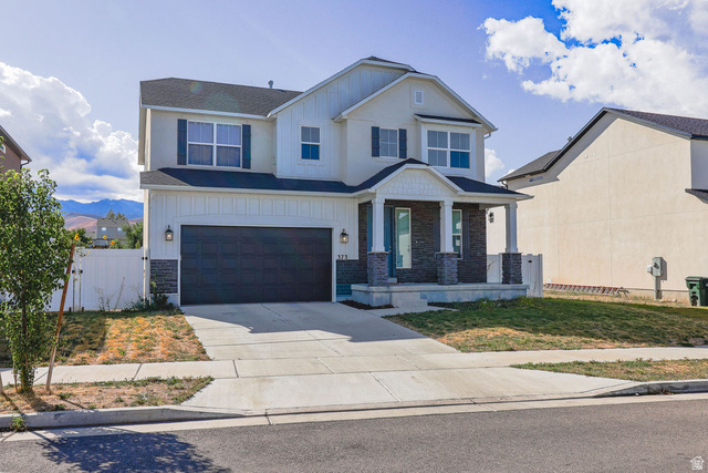 373 Quartz Road Tooele, UT 84074 - Photo 3 of 38 Two-story residence featuring a covered entry porch, dark-toned garage door, white vertical siding accents, and dark window shutters