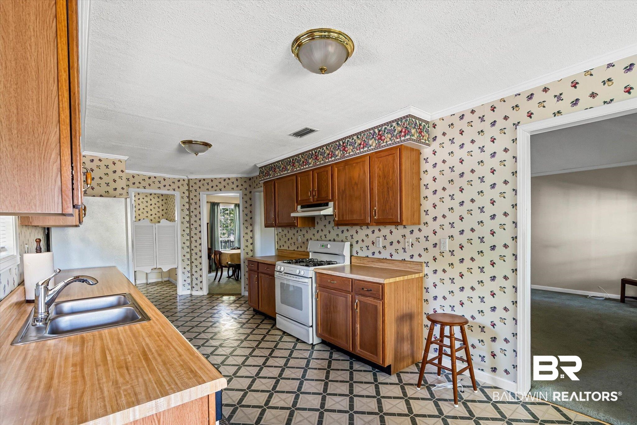 431 Simms Drive Saraland, AL 36571 - Photo 10 of 34 Kitchen with light countertops, white appliances, wallpapered walls, crown molding, and brown cabinetry