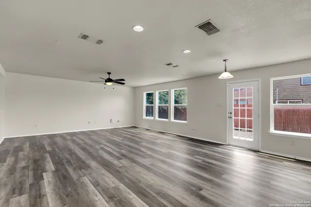 an empty room with wooden floor and windows
