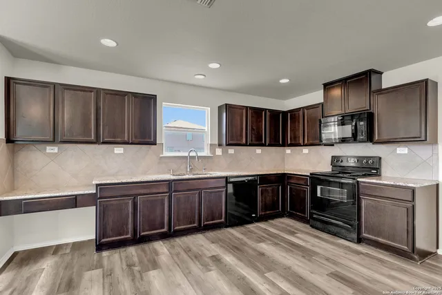 a kitchen with stainless steel appliances granite countertop wooden cabinets a stove top oven a sink and dishwasher