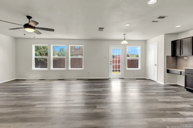 a view of an empty room with a window and wooden floor