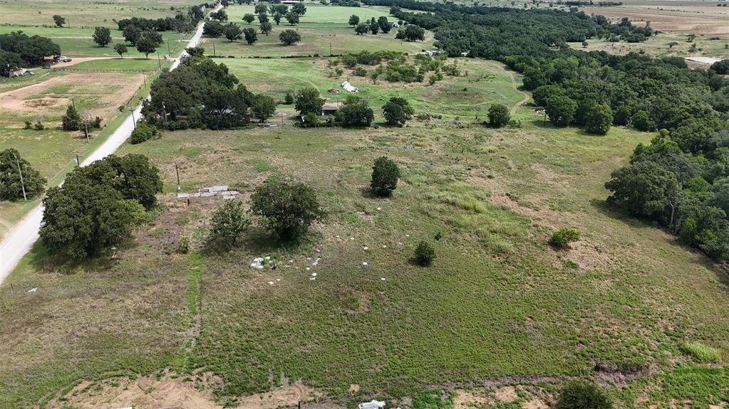 497 Big Sandy Road Newcastle, TX 76372 - Photo 16 of 22 Expansive land parcel featuring a tree-lined perimeter, a partially paved road, and varied topography