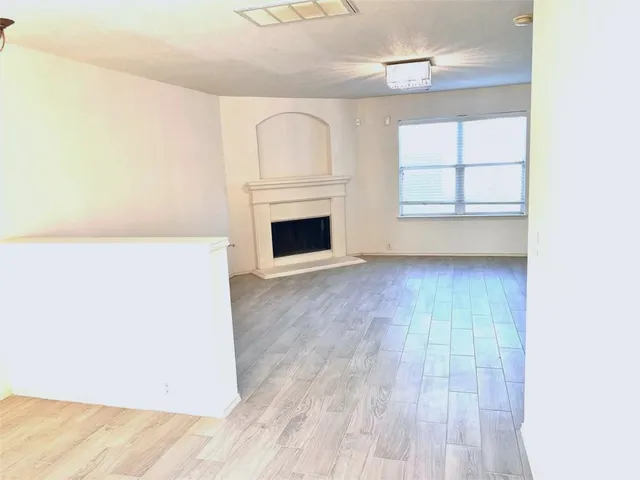 a view of a livingroom with wooden floor and a fireplace