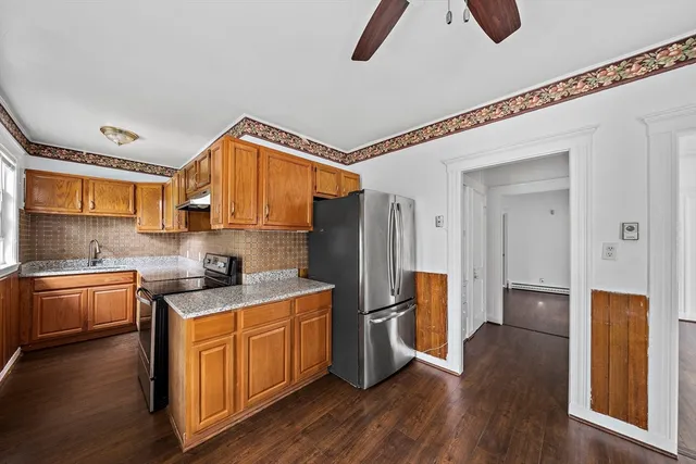 a kitchen with stainless steel appliances granite countertop a refrigerator a sink dishwasher a stove and white countertops with wooden floor