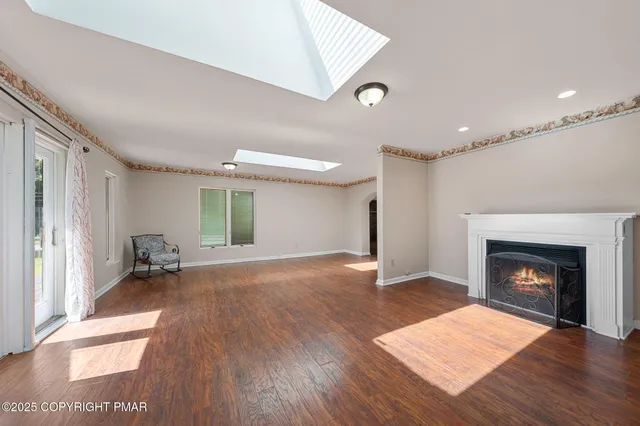 a view of an empty room with wooden floor fireplace and a window