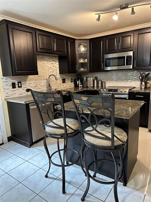 a kitchen with stainless steel appliances kitchen island granite countertop a stove top oven a sink a dining table and chairs