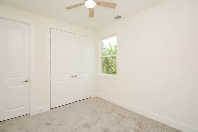 an empty room with a window and a fan