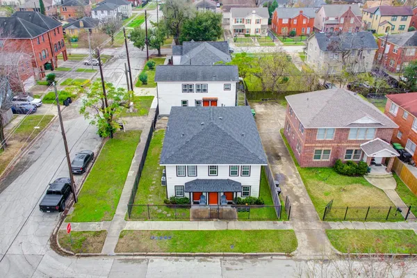 an aerial view of a house with swimming pool and large trees