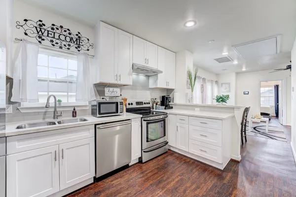 a kitchen with white cabinets sink and stainless steel appliances