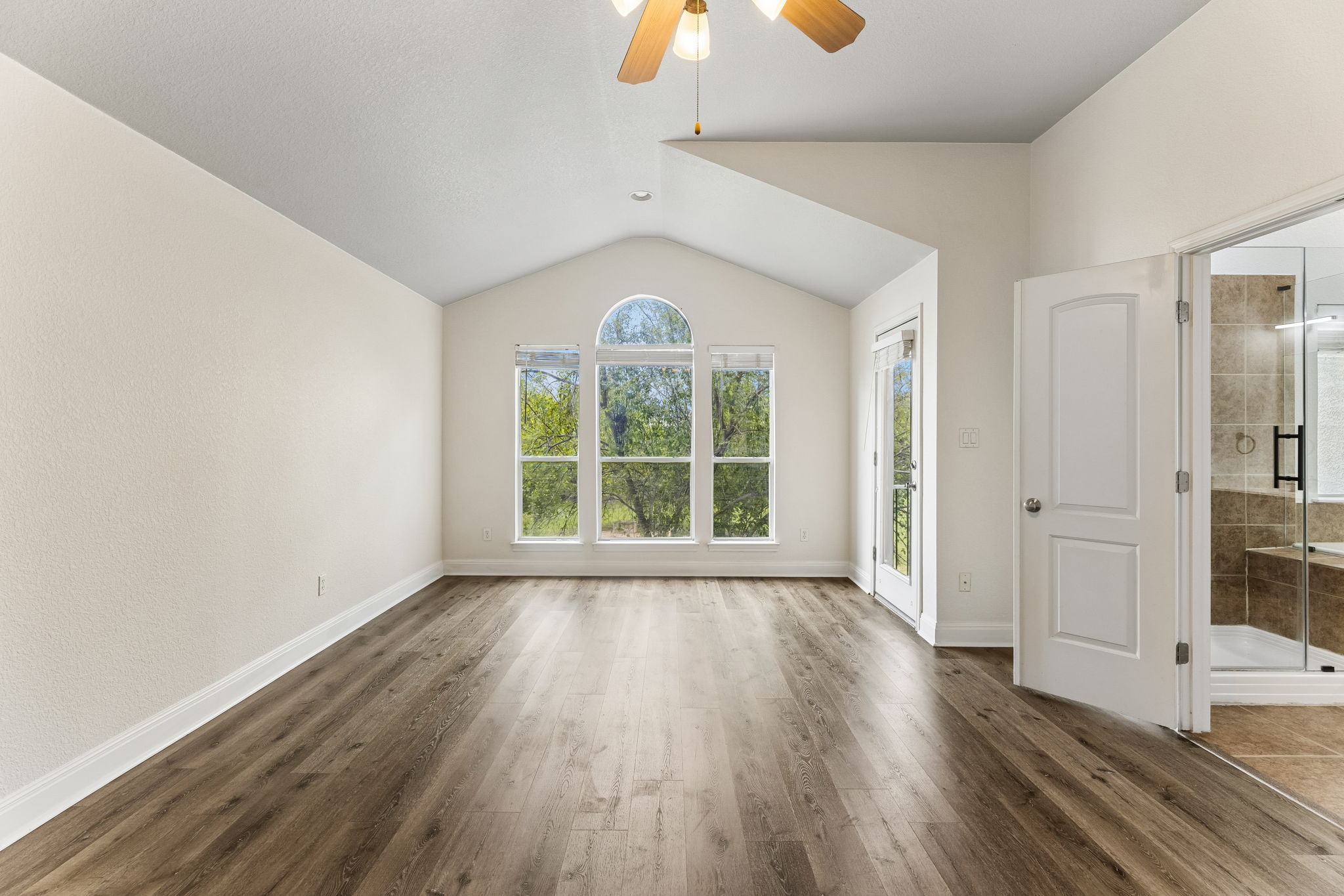 114 Aria Ridge, Unit 802 Lakeway, TX 78738 - Photo 27 of 37 Natural light floods this room, highlighting the beautiful wood flooring and views of mature trees.