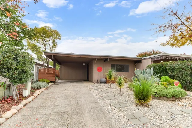 a view of a house with a small yard and a large tree