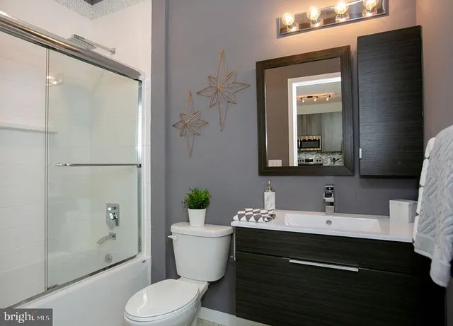 a bathroom with a granite countertop sink toilet a mirror and shower